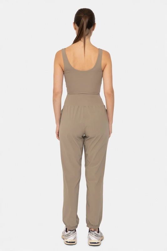 Backside profile of a Woman wearing a beige jumpsuit on a white background