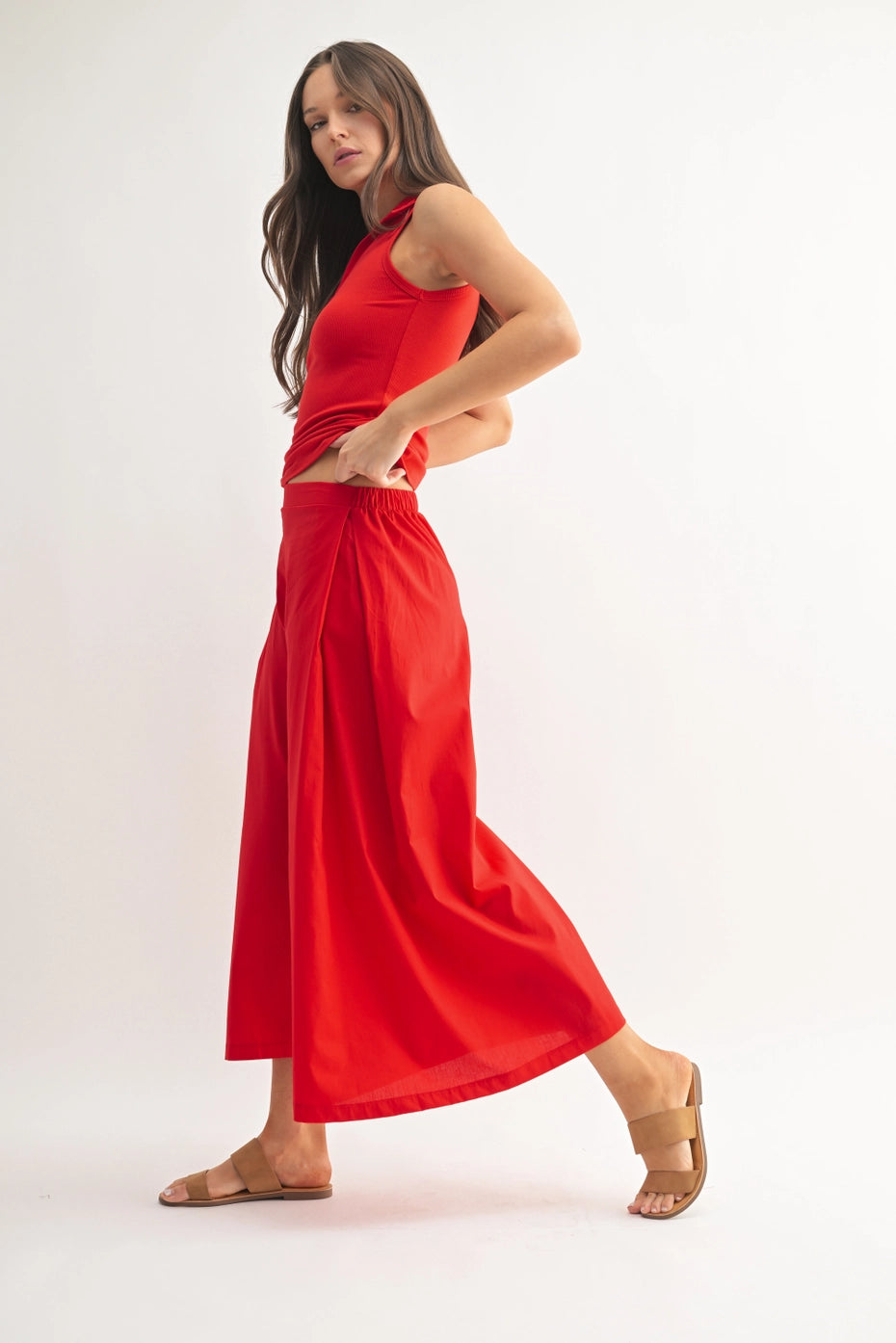 Woman wearing a red sleeveless polo top and matching wide leg pants on a white background