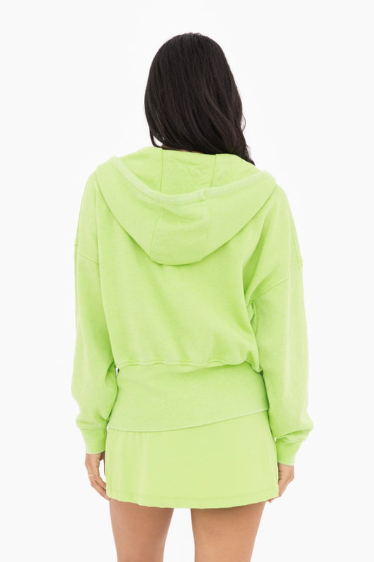 Person wearing a bright green hoodie and skirt set on a white background