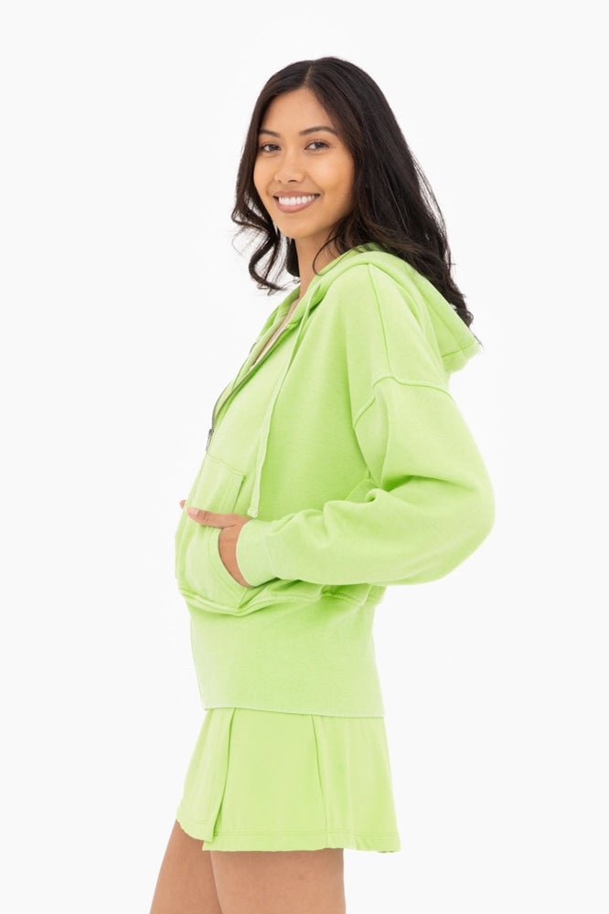 Woman wearing a bright green hoodie and skirt set on a white background
