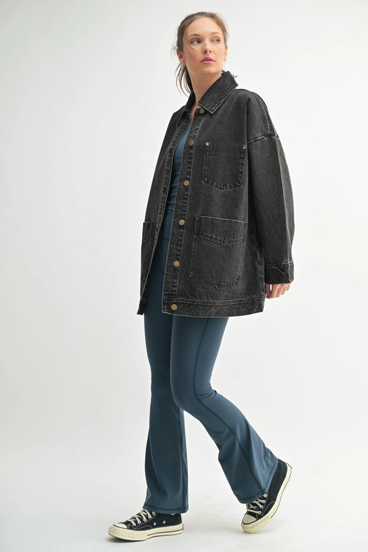 Woman wearing a black denim jacket and blue jeans on a white background