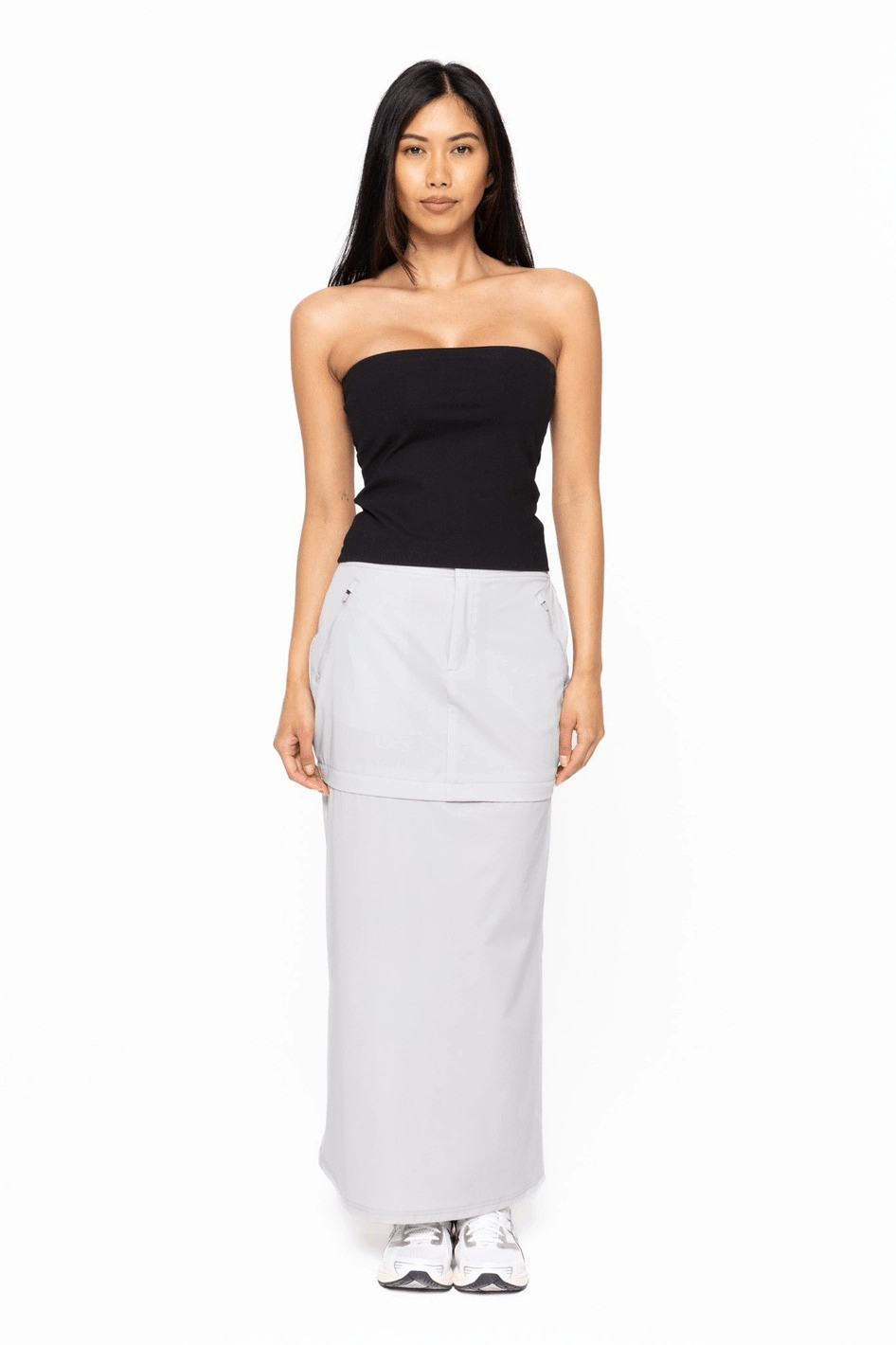 Woman wearing a black strapless top and light gray skirt on a white background