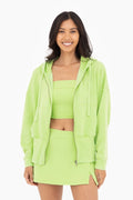 Woman wearing a neon green outfit with a fleece jacket, top, and skirt on a white background
