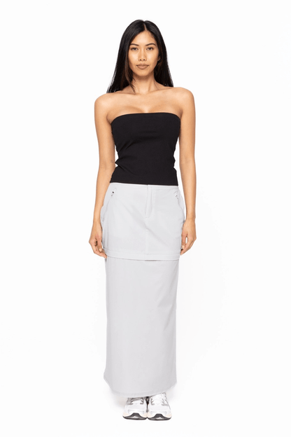 Woman wearing a black strapless top and light gray skirt on a white background